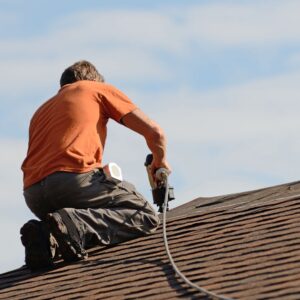 person using nail gun on roof