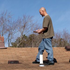 person examining roof with clipboard