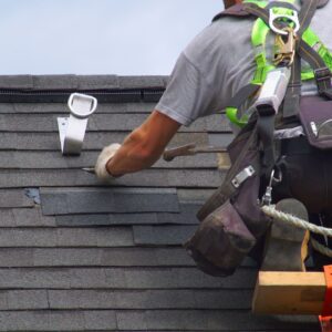 person repairing shingles on roof